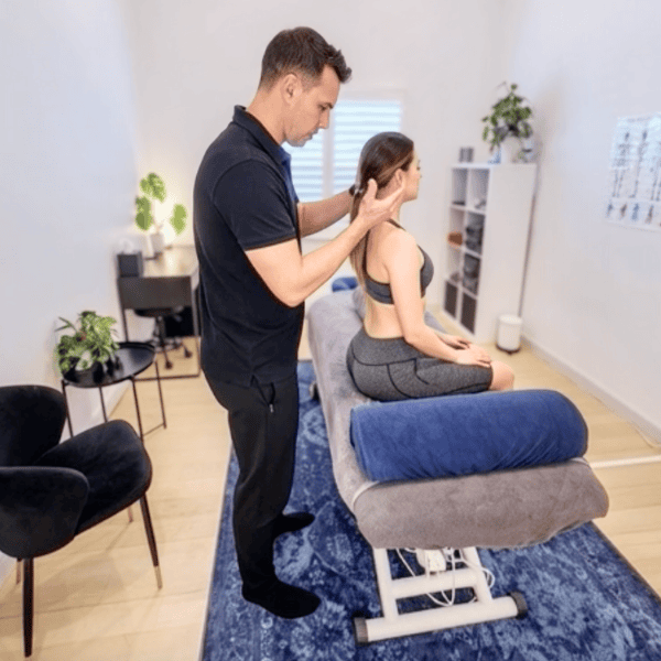 Physiotherapist at Specific Physiotherapy Preston performing a hands-on neck assessment for tension headaches on a seated female patient.