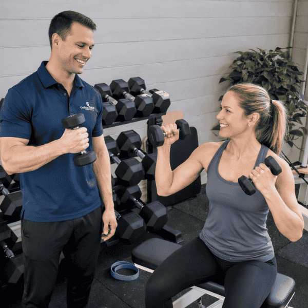 Physiotherapist guiding patient through shoulder strengthening exercises with dumbbells in clinic